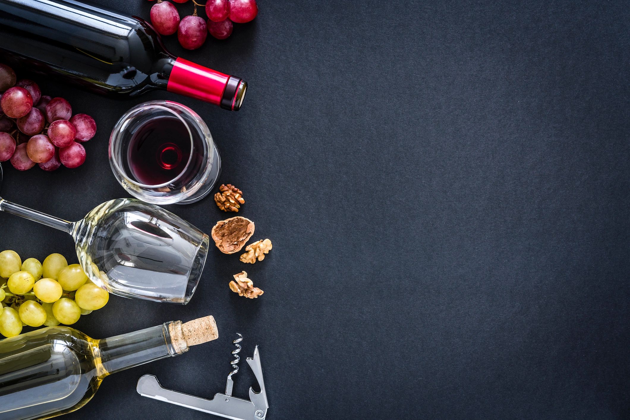 Wine bottles and glasses on black background with copy space
