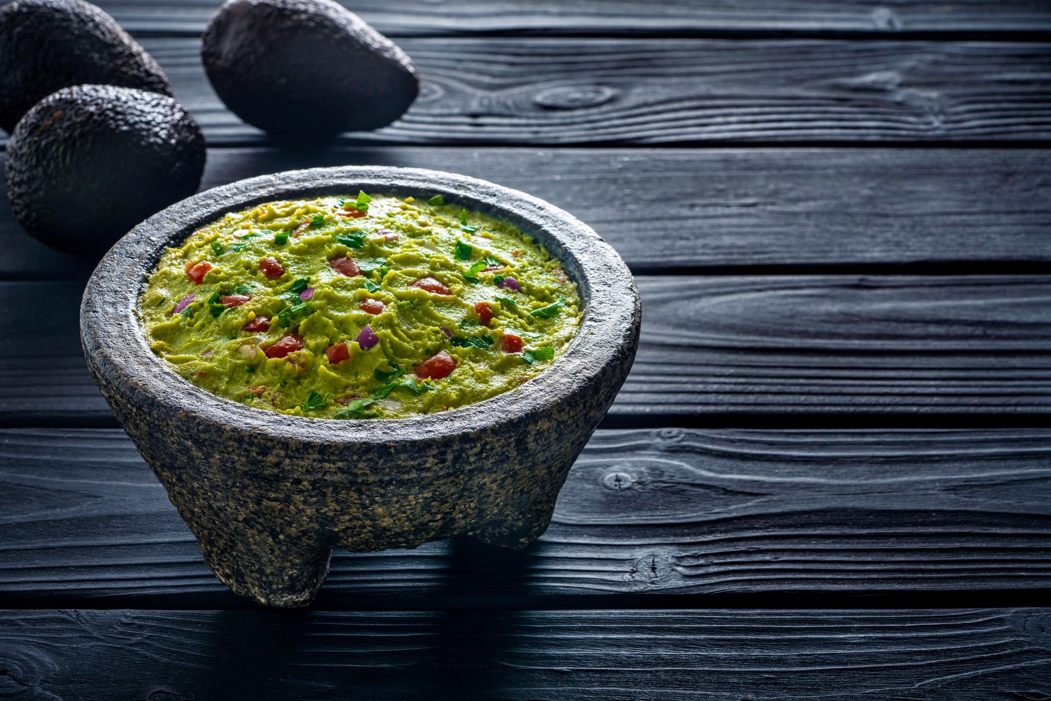 Guacamole in a stone molcajete on dark background